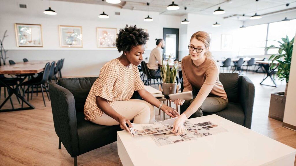 Two women sitting at a table looking at photographs.
