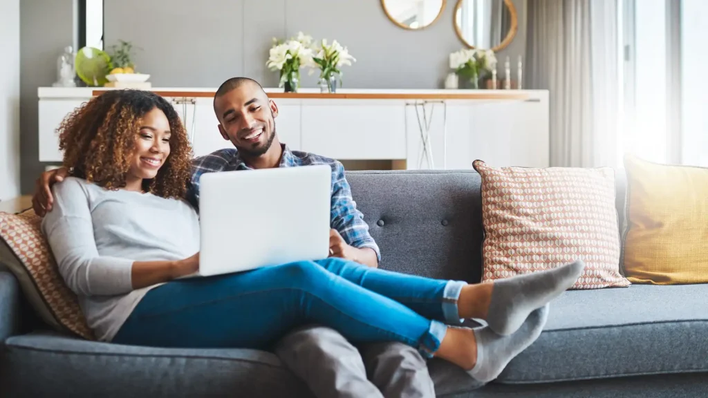 Young couple relaxing on the sofa at home and using a laptop together