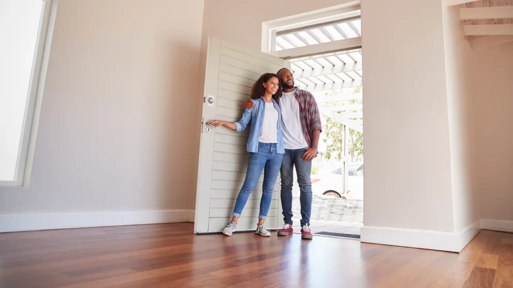 Couple standing at the front door of an empty living room of a home