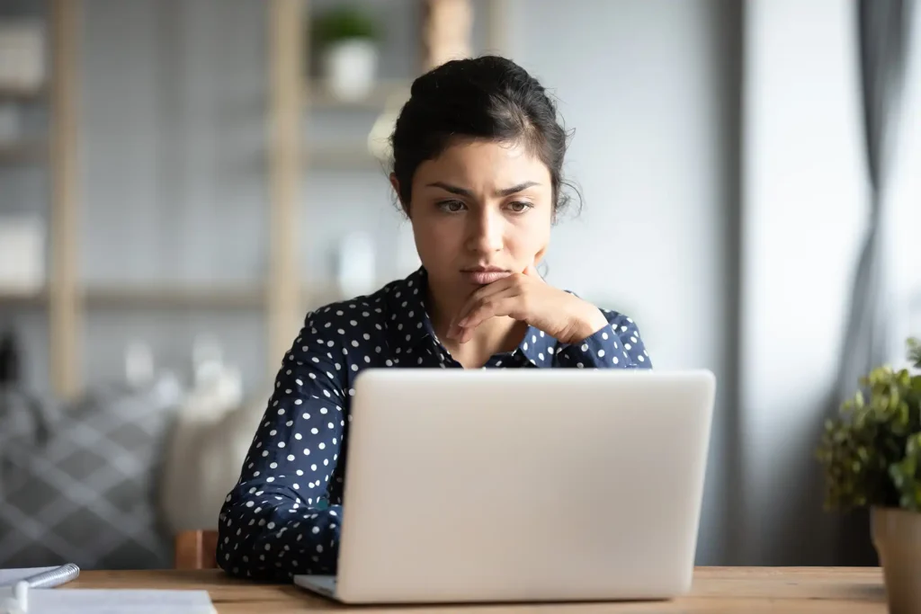 Woman looking serious while looking at laptop screen